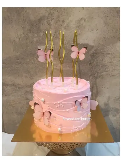 A single tier version of my popular butterfly cake. The soft pink buttercream is decorated with butterflies and accented with tall, elegant golden candles.