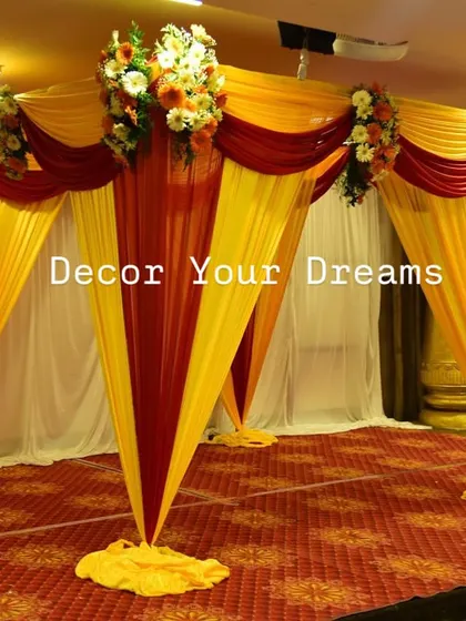 A simple and traditional mandap setup. This decor uses red and yellow drapes with floral bouquets, perfect for a small wedding ceremony or muhurtham at home.