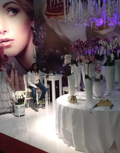 This elegant display at a European expo combines fashion and flowers, with a mannequin's dress and beautiful white orchids. It's a great example of thematic event design.