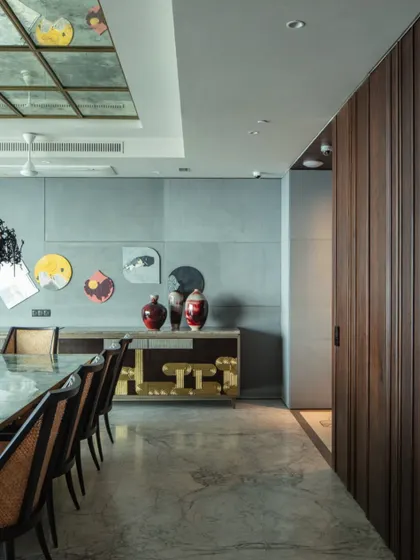 A signature sideboard by Furgonomics, featuring 'Thathera' metalwork, stands in the dining room. The door to the powder room is seamlessly hidden within the wood-paneled wall, showcasing our attention to integrated design.