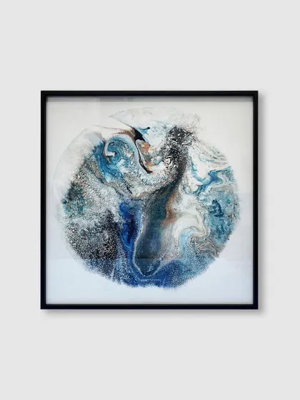 This abstract artwork, reminiscent of a swirling planet, is elegantly contained within a square black metal frame, adding a touch of modern sophistication.