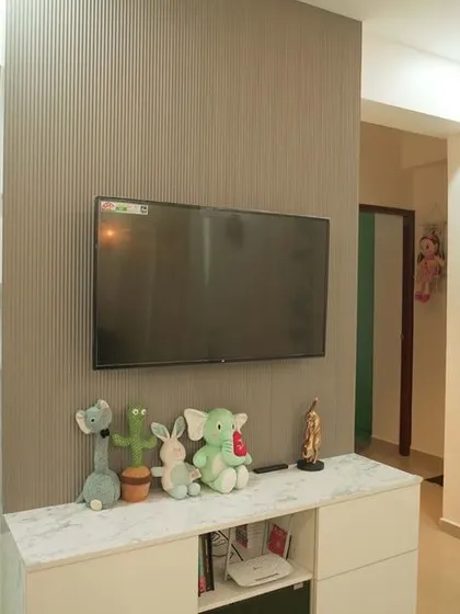 This view shows the TV mounted on a textured grey wall, with decorative white panels on the adjacent wall. The setup is simple, modern, and stylish.