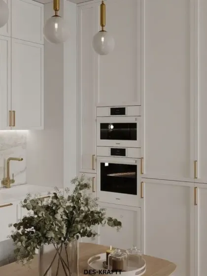 This close-up shows the sleek, handleless white cabinetry with integrated ovens and gold fixtures, demonstrating our commitment to clean lines and high-end finishes.