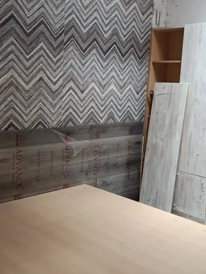 Another view of the bedroom work in progress, showing the textured wallpaper and initial furniture placement. Our team's dedication ensures projects move forward, even on weekends.