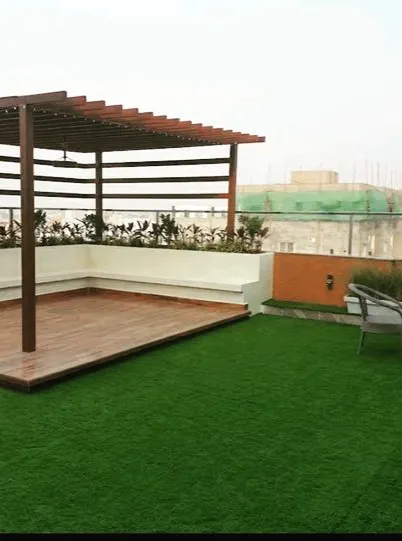 A simple yet effective rooftop design. We installed a pergola with built-in seating over a wooden deck, surrounded by a large expanse of low-maintenance artificial turf, perfect for an urban environment.