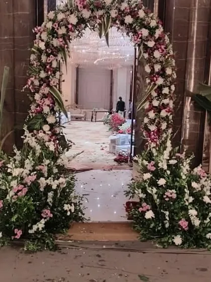 A classic floral archway I created for the entrance to a wedding hall. The arch is made with a mix of white, pink, and green fresh flowers and foliage.