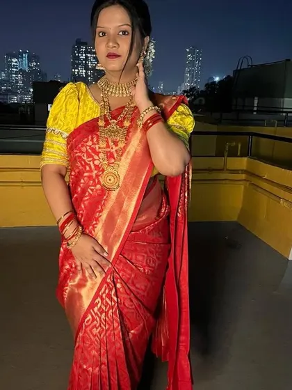 This client is posing against the city skyline in her red Banarasi saree. The Nivi drape is versatile and looks stunning in both traditional and modern settings.