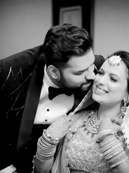 A sweet black and white photo of a brother giving his sister, the bride, a kiss on the cheek. A beautiful, candid moment of sibling love on the wedding day.