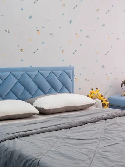 A playful kid's room with a blue diamond-tufted headboard and a cozy window seat for reading and play.