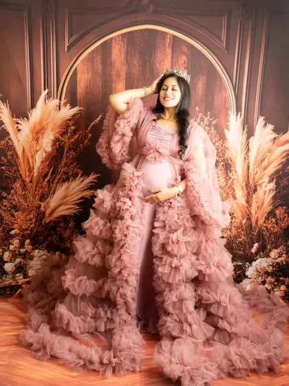 A regal portrait with a crown and a magnificent ruffled gown. The pose exudes confidence and celebrates the queen that every mother is.