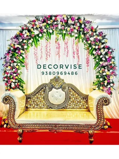 For clients who prefer a comfortable sofa instead of a swing, we create elegant stage setups like this one. A grand floral arch made of roses and orchids frames the seating area, creating a perfect photo opportunity for the parents-to-be.