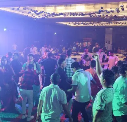 A corporate Diwali celebration at the Sheraton Grand. The ballroom is filled with employees dancing under a professional lighting setup.