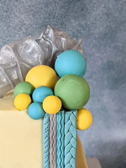 This shot highlights the arrangement of colorful chocolate spheres and edible rice paper sails on a modern, square-tiered birthday cake. It shows how I play with color, shape, and texture to create a unique design.
