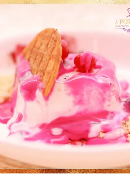 This vibrant dessert features a creamy panna cotta base topped with a bright pink berry sauce and a delicate wafer. It's a visually appealing and delicious option.