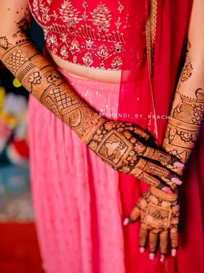 A lovely shot of a bride's back-hand mehndi. The design includes personalized elements and coordinates perfectly with her engagement outfit.