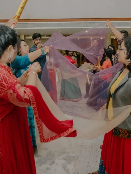 Friends and family create a tunnel with dupattas on the dance floor, adding a fun, interactive element to the party.