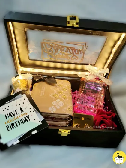 An elegant birthday hamper box with a transparent, light-up lid. Inside, I've placed a beautiful journal, perfume, and chocolates for a luxurious feel.