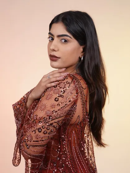 A close-up of the rust-colored corset set. The intricate beadwork and modern silhouette make it a show-stopping choice for a sangeet or cocktail look.