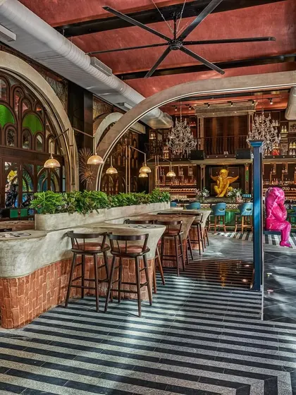 An overview of Suzy Q's interior, showing the interplay of different zones. We used bold black-and-white chevron flooring to ground the space, while Gothic-style arches and stained-glass windows add a layer of theatricality.
