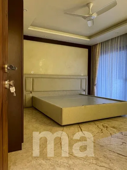 Entering this bedroom, you are greeted by warm tones and simplicity. The design uses a neutral palette and clean lines to create a restful and uncluttered environment, set against a beautiful marble floor.
