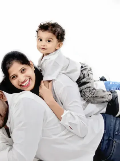 A fun and playful family pose, with the baby riding on his mother's back while she lies on his father's back.