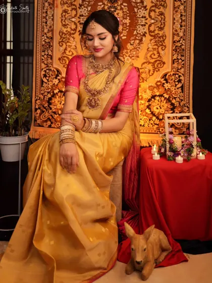 A full-length portrait from a concept shoot, featuring a model in a beautiful golden saree. The carefully arranged props like candles and a decorative deer add a touch of magic.