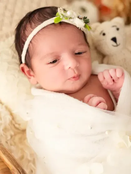 A close-up of the baby girl in the boho basket, making another cute expression.
