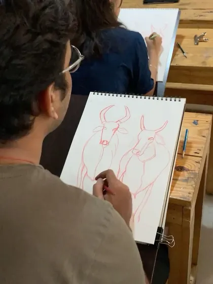 From another angle, we see a student working on their bull sketch. Our classroom setup allows for individual focus while being part of a collective, creative energy.