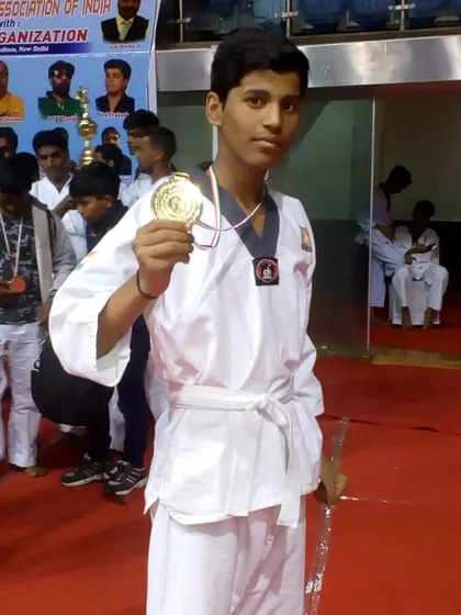 A young student proudly displays his gold medal after winning his category at the national championship.