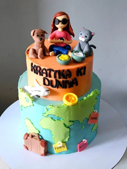 A different view of the two-tiered "Krattika Ki Duniya" cake, showing how the travel-themed bottom tier and the personalized top tier come together to tell a complete story.