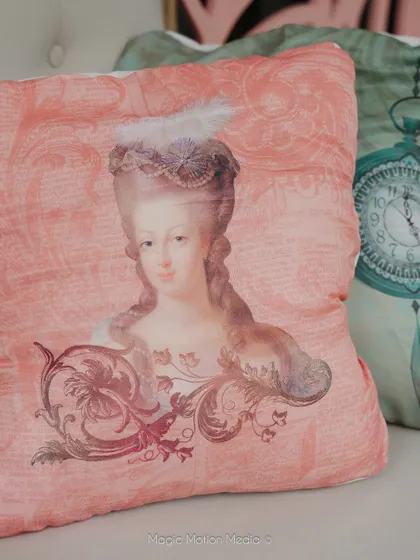 A custom-printed cushion featuring a portrait of Marie Antoinette, a perfect detail for a Bridgerton-themed party.