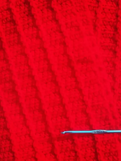 A close-up of the rich red crochet fabric. The simple stitches create such a lovely and classic design.