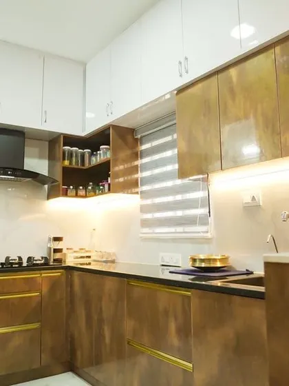 A wider view of the bronze-finish kitchen, showing the efficient layout and the combination of closed cabinets and open corner shelves. The design is both glamorous and highly functional.