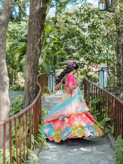 A shot of the bride walking along a rustic pathway, her colorful lehenga creating a beautiful contrast with the greenery.