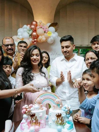 The cake cutting is a highlight of any celebration. The family gathers around for this sweet moment at a boho-themed baby shower, with two beautiful cakes for the little one on the way.
