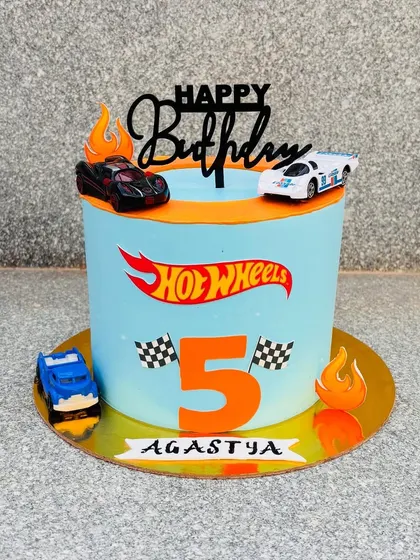 A Hot Wheels theme cake for a 5-year-old car enthusiast. This cake is decorated with the Hot Wheels logo and real toy cars that can be kept after.