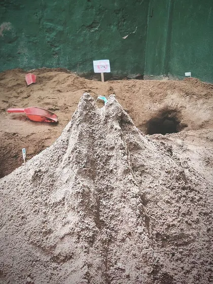 A magnificent volcano rises from the sandpit, complete with tunnels and caves. The children's constructions are often elaborate and detailed, reflecting their rich inner worlds.