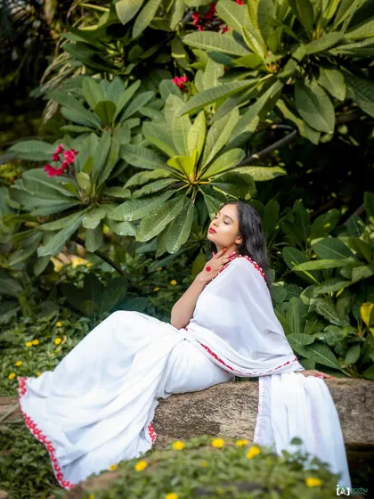 Serenity in nature. This portrait, taken in a lush green setting, uses soft, natural light to create a peaceful and elegant mood, highlighting the simple beauty of the white saree.