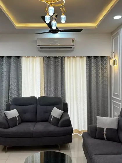 Another angle of the sophisticated living room, showing the layered curtains and warm lighting that add to the room's cozy and upscale feel.
