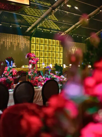 A blurred foreground of flowers leads the eye to the beautifully lit bar and stage area of the Sangeet.