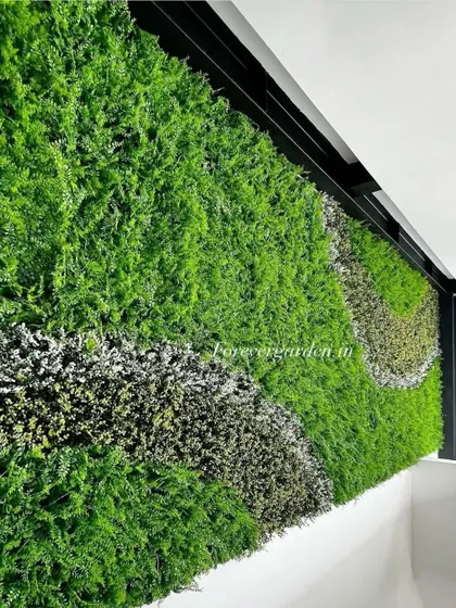 A green wall with a wave-like pattern created using different types of foliage, installed at the top of a wall near the ceiling.