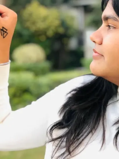A client showing off a geometric symbol painted on their hand. These small, sharp designs are very popular.