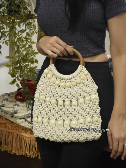 This macramé tote bag features a beautiful wooden handle and is embellished with beads for a sophisticated look. It’s a spacious and stylish bag, perfect for daily use.