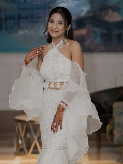 The full view of Kaaya's stunning white outfit. The makeup is kept minimal and glowing to balance the dramatic sleeves.