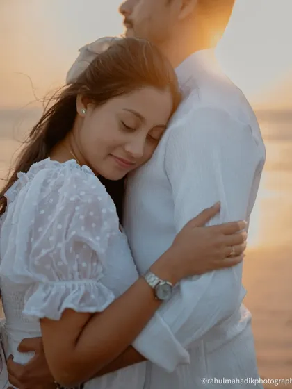 A soft and tender moment during a sunset beach shoot. The bride rests her head on the groom's chest, and the warm, golden light creates a beautifully romantic and peaceful atmosphere.