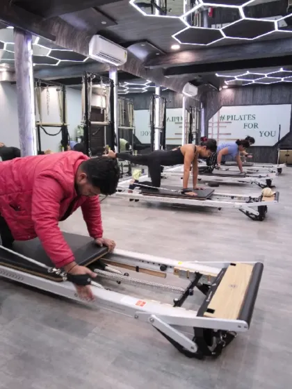 A full view of a busy class, with clients at different stages of a Reformer exercise. It shows the inclusive and active atmosphere of our group sessions, where everyone is welcome.