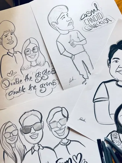 A flat lay of several finished caricatures, showing the variety of my work, from individuals to couples and groups.