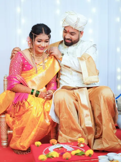 A candid moment of the couple seated during their wedding ceremony, sharing a quiet smile.
