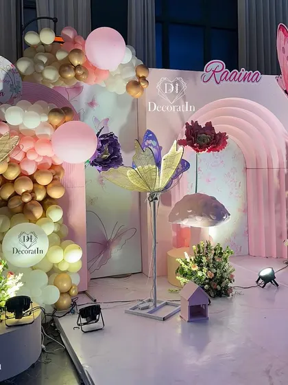 A side view of the stage, focusing on the left side's balloon arrangement and the custom-printed balloons featuring the DecoratIn logo and the birthday girl's name.