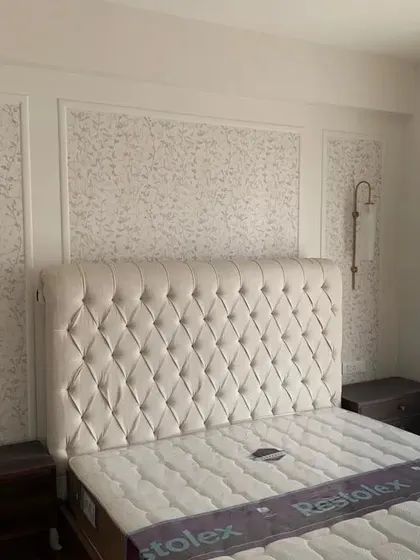 Sneak peek into a hectic handover. This bedroom features a luxurious tufted headboard against a subtly patterned wallpaper and elegant wall sconces.